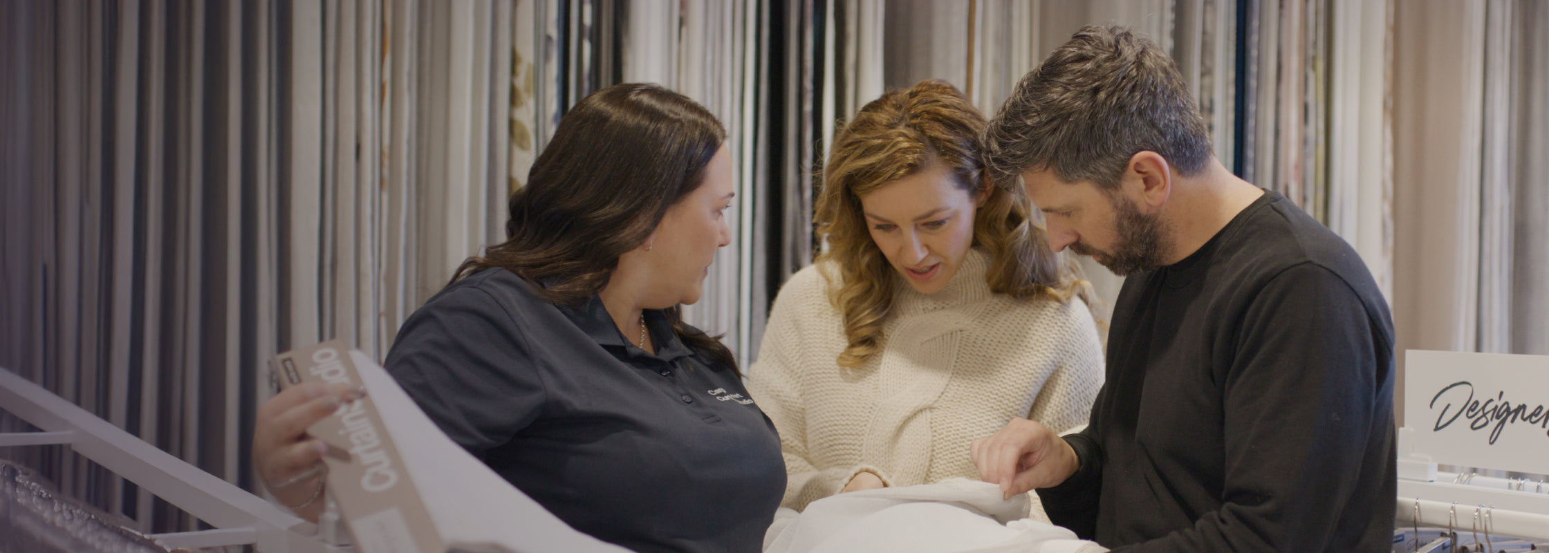 Helpful staff member talking with customers about curtains
